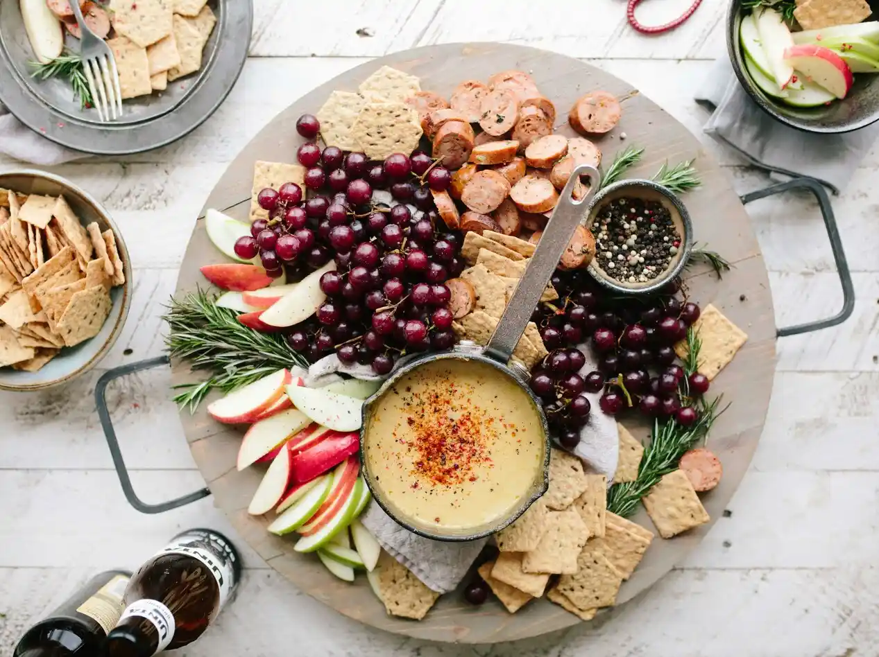 Cheese fondue platter with fruits and crackers.