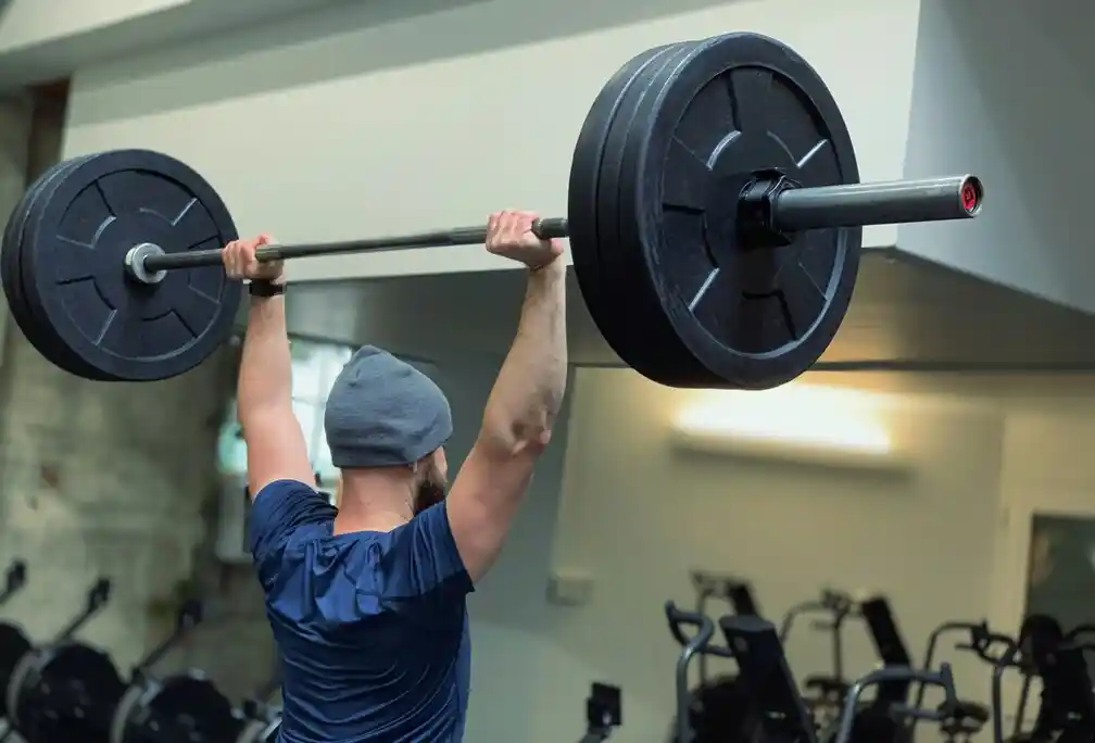 Man lifting heavy barbell in gym