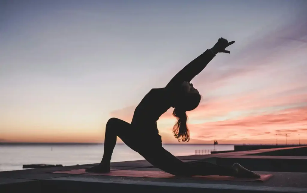 Woman doing yoga at sunset by the sea.