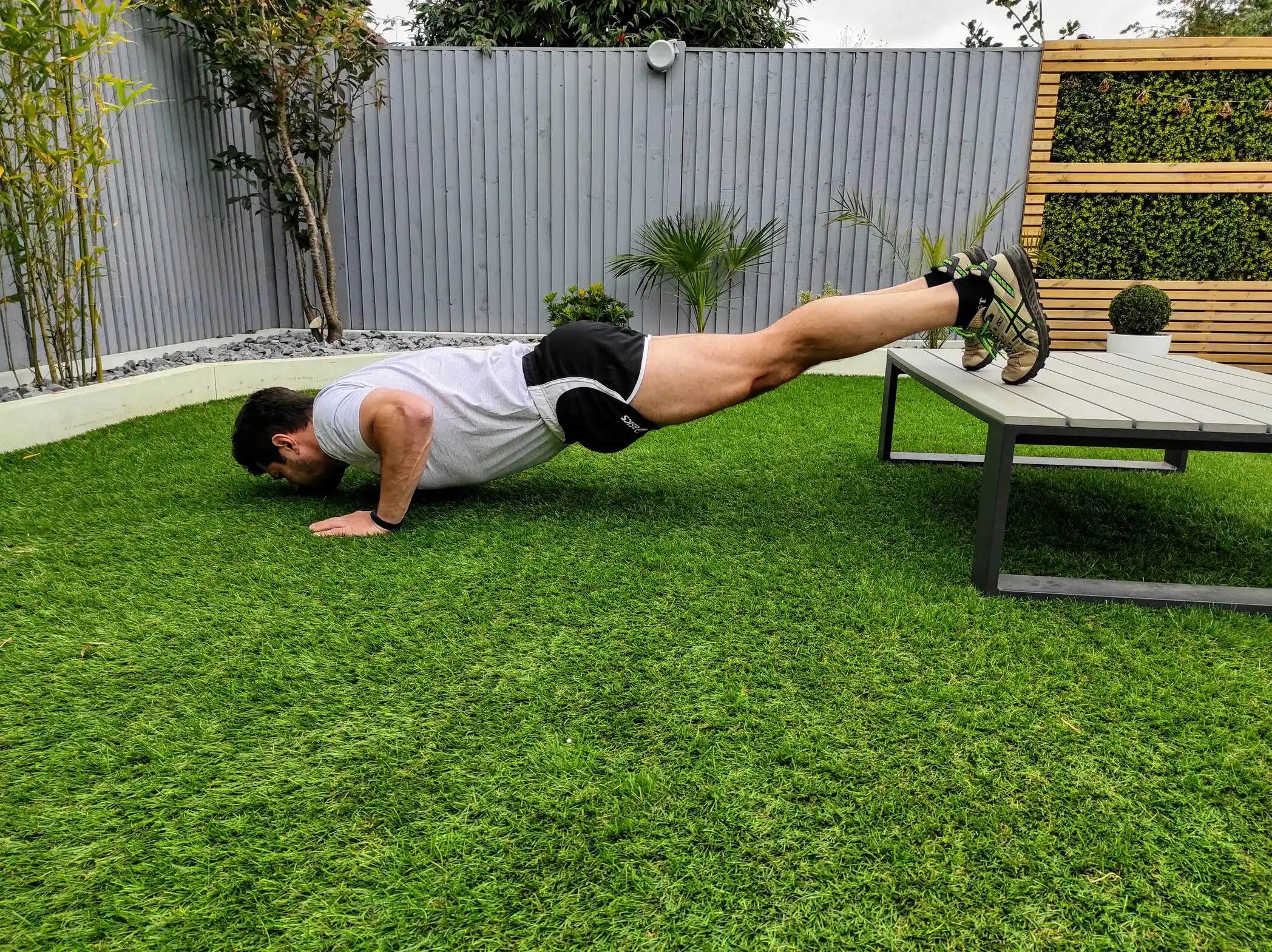 Man doing incline push-up on outdoor table.