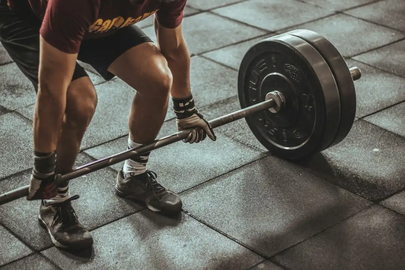 Person lifting a heavy barbell in gym.