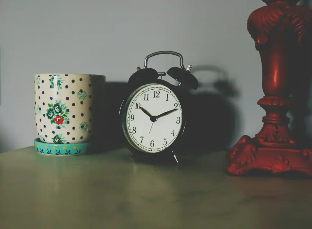 Vintage alarm clock next to floral mug