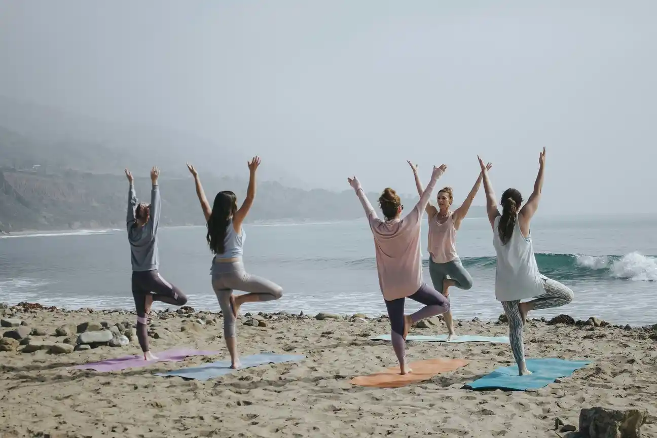 Group doing yoga on a beach.