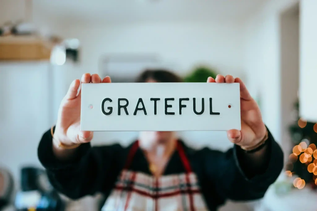 Person holding 'Grateful' sign indoors